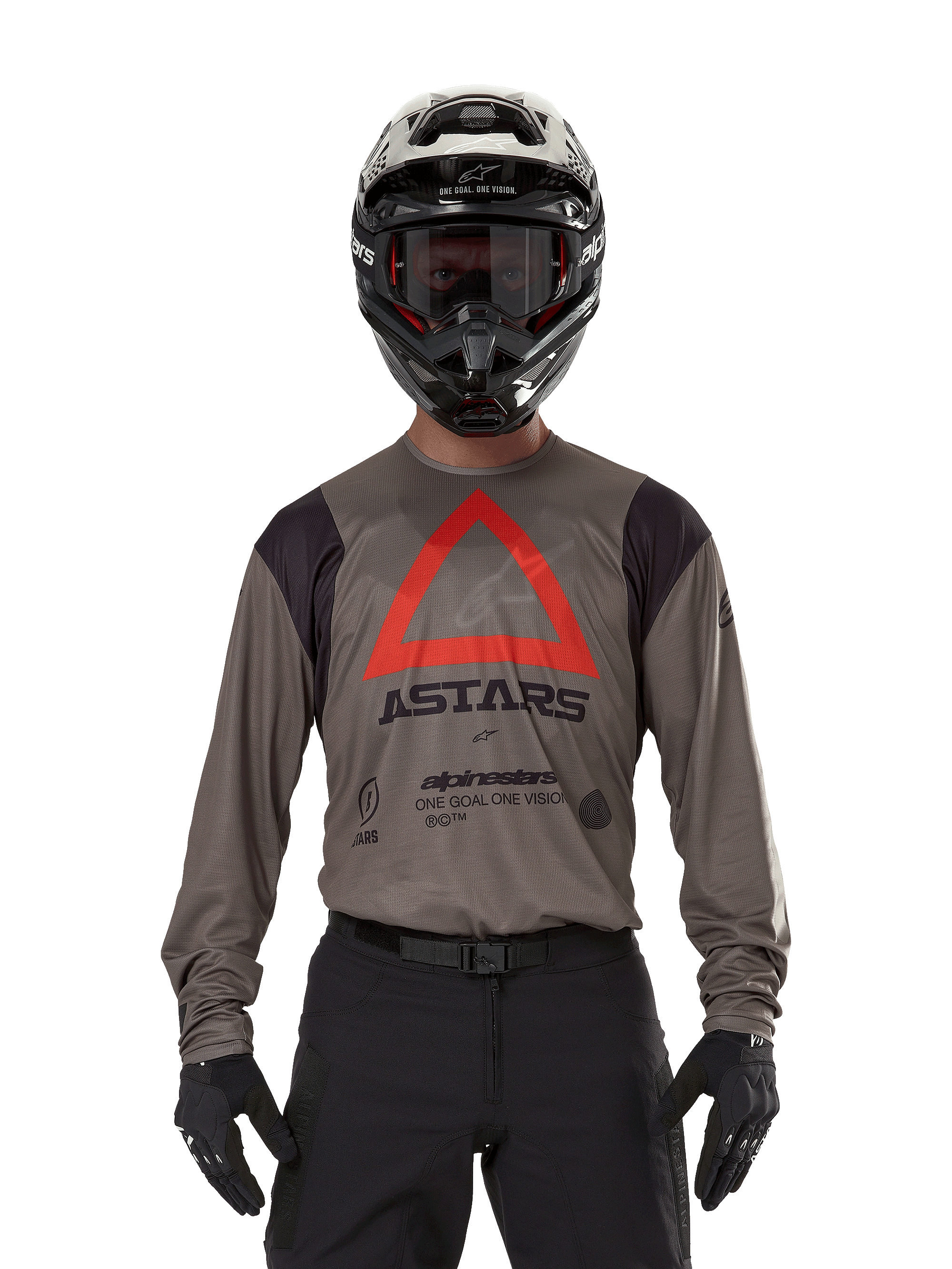 Motocross-Fahrer im Alpinestars Techdura Jersey in Falcon Brown, mit einem markanten roten Dreieck und „ASTARS“-Branding auf der Brust, kombiniert mit schwarzer Hose, schwarzem Helm mit Brille und schwarzen Handschuhen, komplette Enduro-Rennausrüstung.
