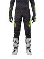 Alpinestars 2024 Techstar Rantera Hose, Motocross-Hose, Schwarz, Navy und Neongelb, getragen mit passendem Langarm-Trikot, Handschuhen und weißen Motocross-Stiefeln, mit auffälligen neongelben Akzenten und abstraktem dunklem Muster.