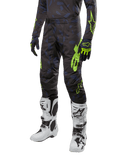 Alpinestars 2024 Techstar Rantera Hose, Motocross-Hose, Schwarz, Navyblau und Neongelb mit Camouflage-Muster und neongrünen Logos, getragen mit passenden Handschuhen und weißen Stiefeln, strapazierfähiges Racing-Fit-Design für Offroad-Performance