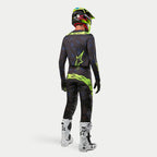 Alpinestars 2024 Techstar Rantera Trikot, Motocross-Trikot, Schwarz, Navy und Neon-Gelb, kombiniert mit passender Hose, weiß-schwarzen Stiefeln und einem neon-gelben Helm, Rückansicht in kompletter Offroad-Rennausrüstung