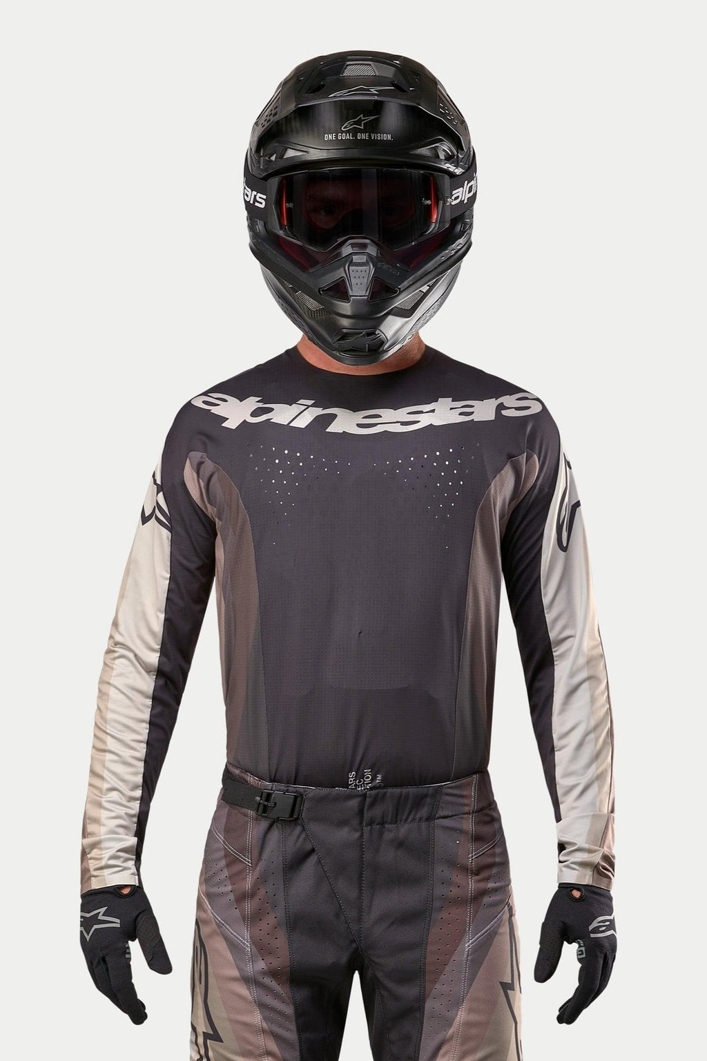 Alpinestars 2024 Techstar Pneuma Trikot, Motocross-Trikot, Dark Sand und Iron Dust Gray, getragen mit passender Motocross-Hose und einem schwarzen Helm, mit markantem Alpinestars-Logo auf der Brust und lasergeschnittenen Belüftungsperforationen, Performance-Offroad-Rennausrüstung