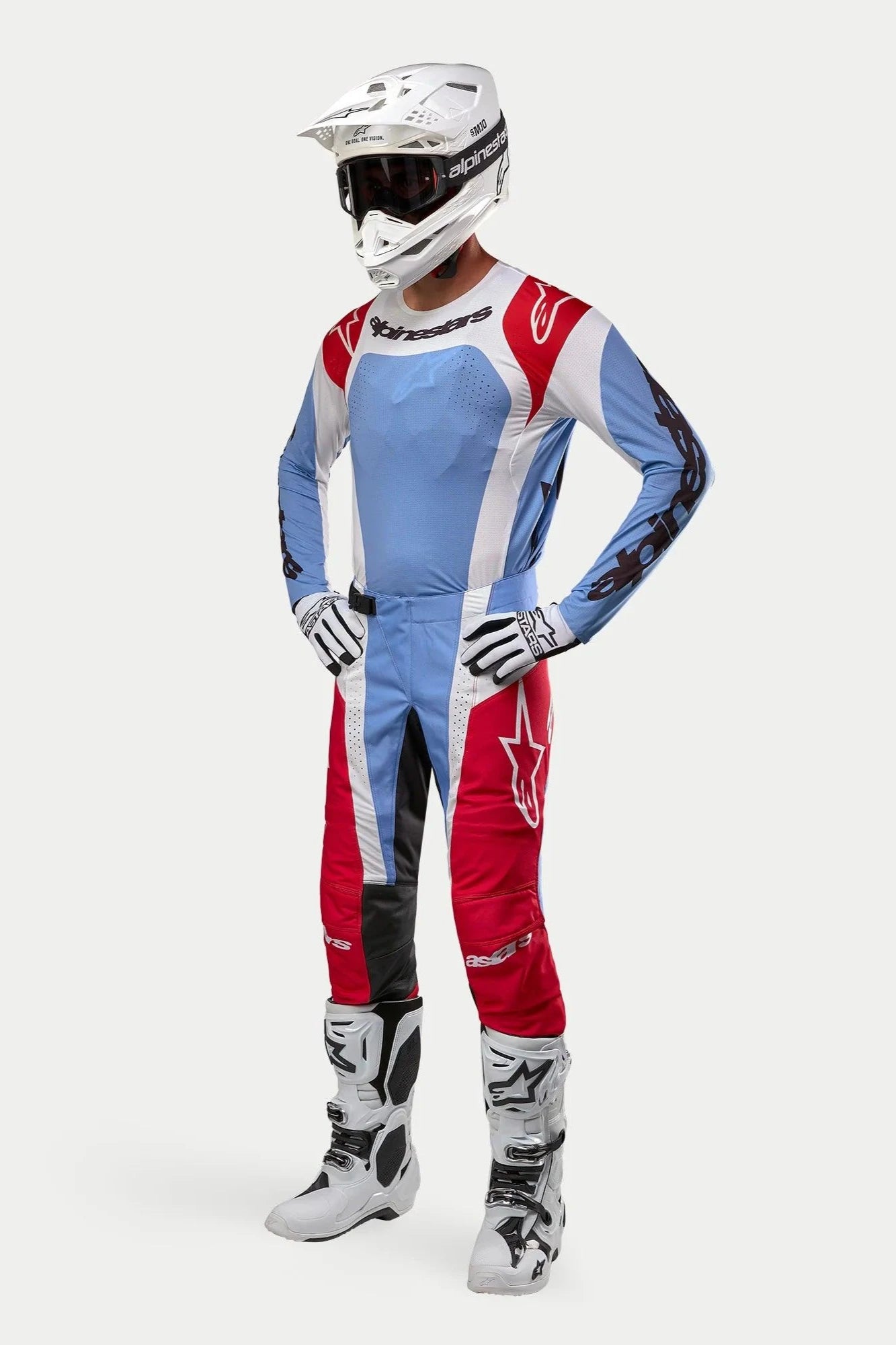 Motocross-Fahrer in Alpinestars 2024 Techstar Ocuri Ausrüstung, Trikot und Hose in Hellblau, Mars-Rot und Weiß, weißer Helm mit Goggles, weiß-schwarze Handschuhe und Stiefel, professionelles Rennoutfit für Offroad-Performance