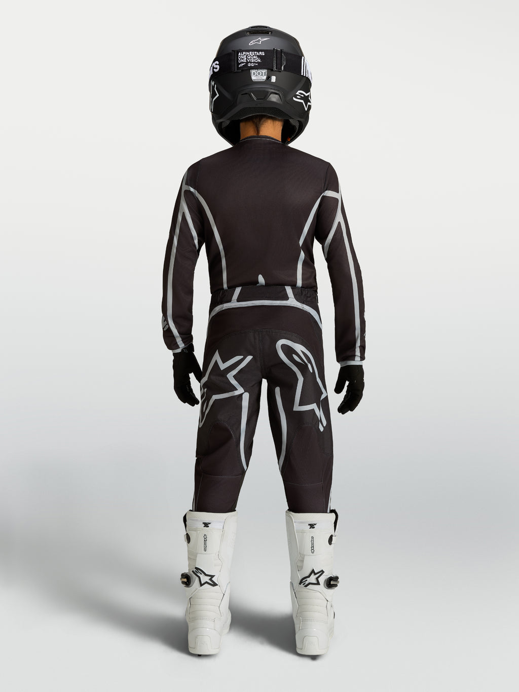Alpinestars Fluid Apex V2 Jugend-Trikot und Gear Set, Motocross-Kombi in Schwarz und Silber, weiße Stiefel, Rückansicht.