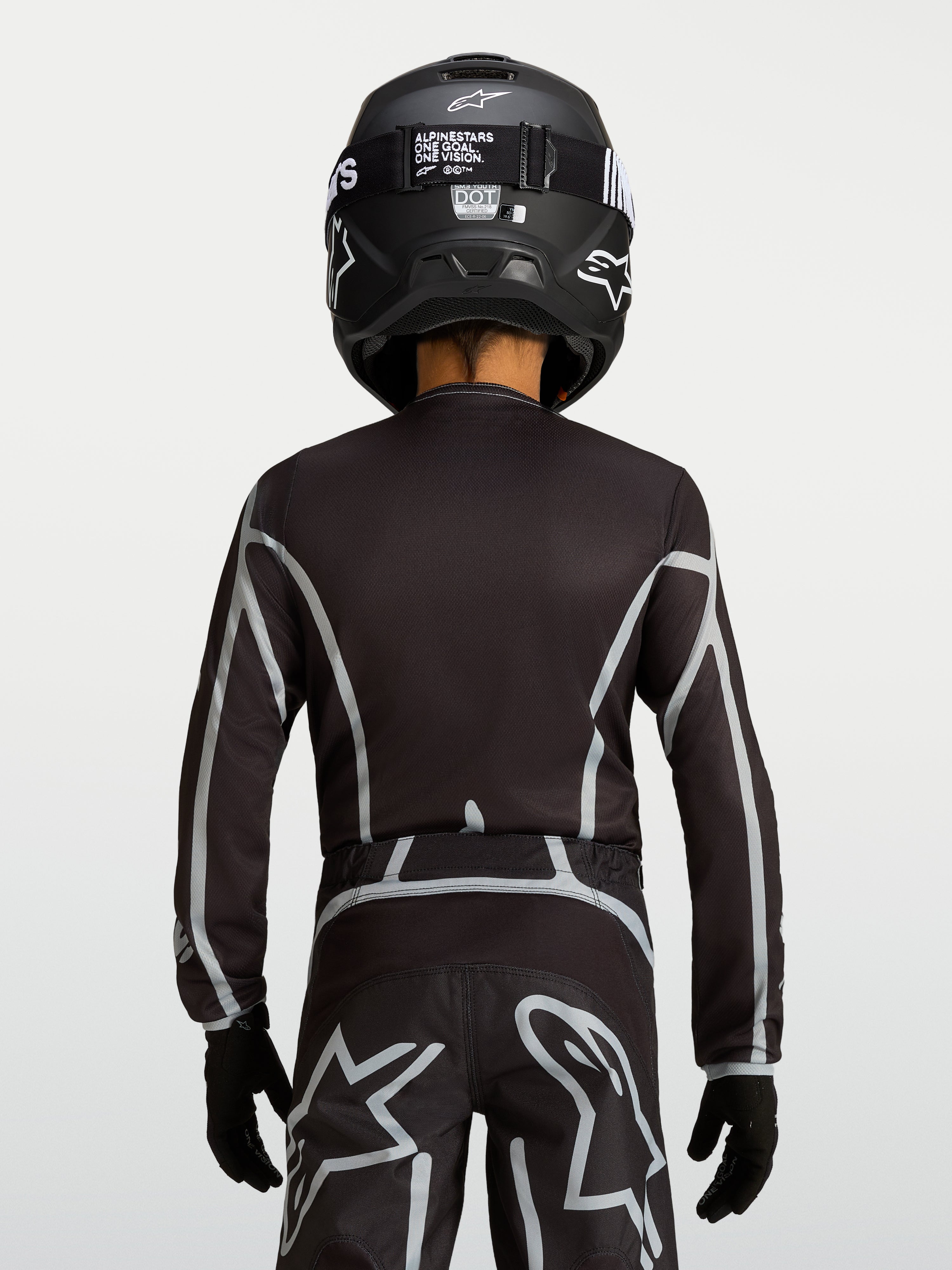 Alpinestars Fluid Apex V2 Jugend-Trikot, Motocross-Oberteil in Schwarz und Silber, ergonomische Passform mit verlängerter Rückenpartie, Rückansicht.