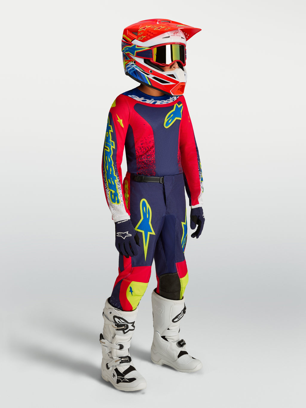 Alpinestars Jugend-Fluid Drag Gear Set 2027, Motocross-Rennbekleidung in Dunkelblau und Feuerrot mit weißen Stiefeln.