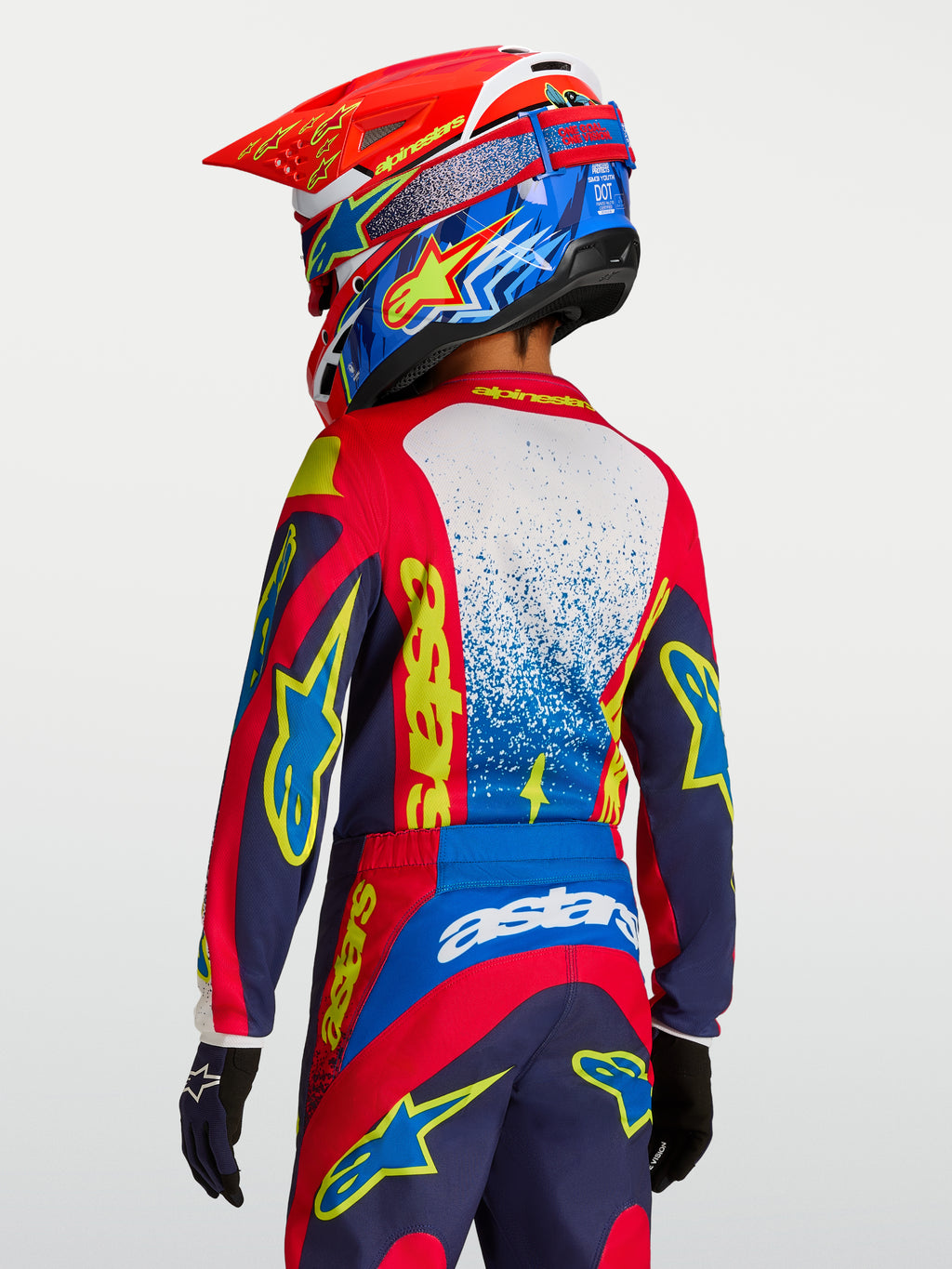 Alpinestars Fluid Jugend-Trikot Drag, Motocross-Trikot in Rot und Navyblau mit gelben Grafiken, Rückansicht auf dem Fahrer.