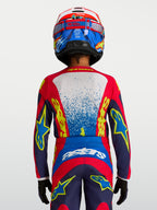 Alpinestars Fluid Jugend-Trikot Drag 2027, technisches Motocross-Trikot in Blau und Rot, Rückansicht auf einem jungen Fahrer, feuchtigkeitsableitendes Material, ergonomischer Schnitt für Offroad-Rennen.