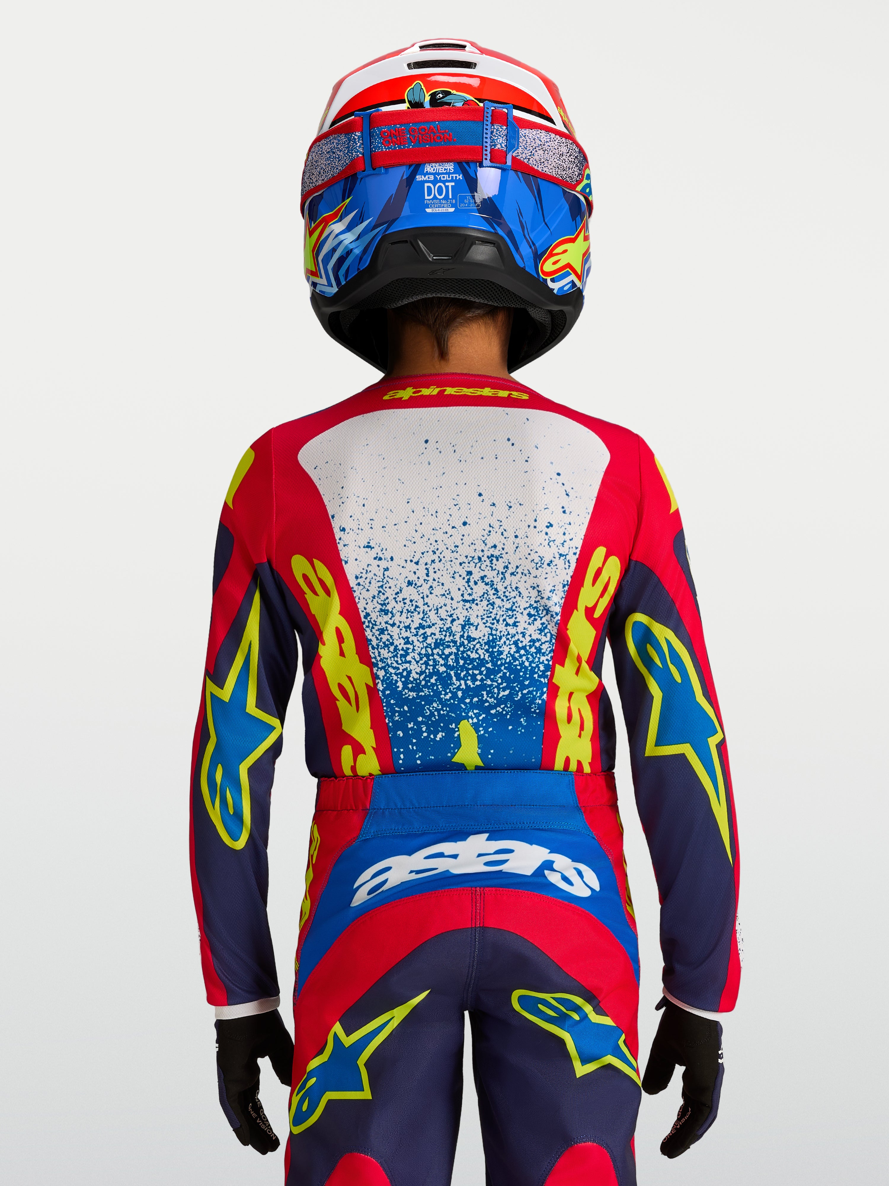 Alpinestars Fluid Jugend-Trikot Drag 2027, technisches Motocross-Trikot in Blau und Rot, Rückansicht auf einem jungen Fahrer, feuchtigkeitsableitendes Material, ergonomischer Schnitt für Offroad-Rennen.