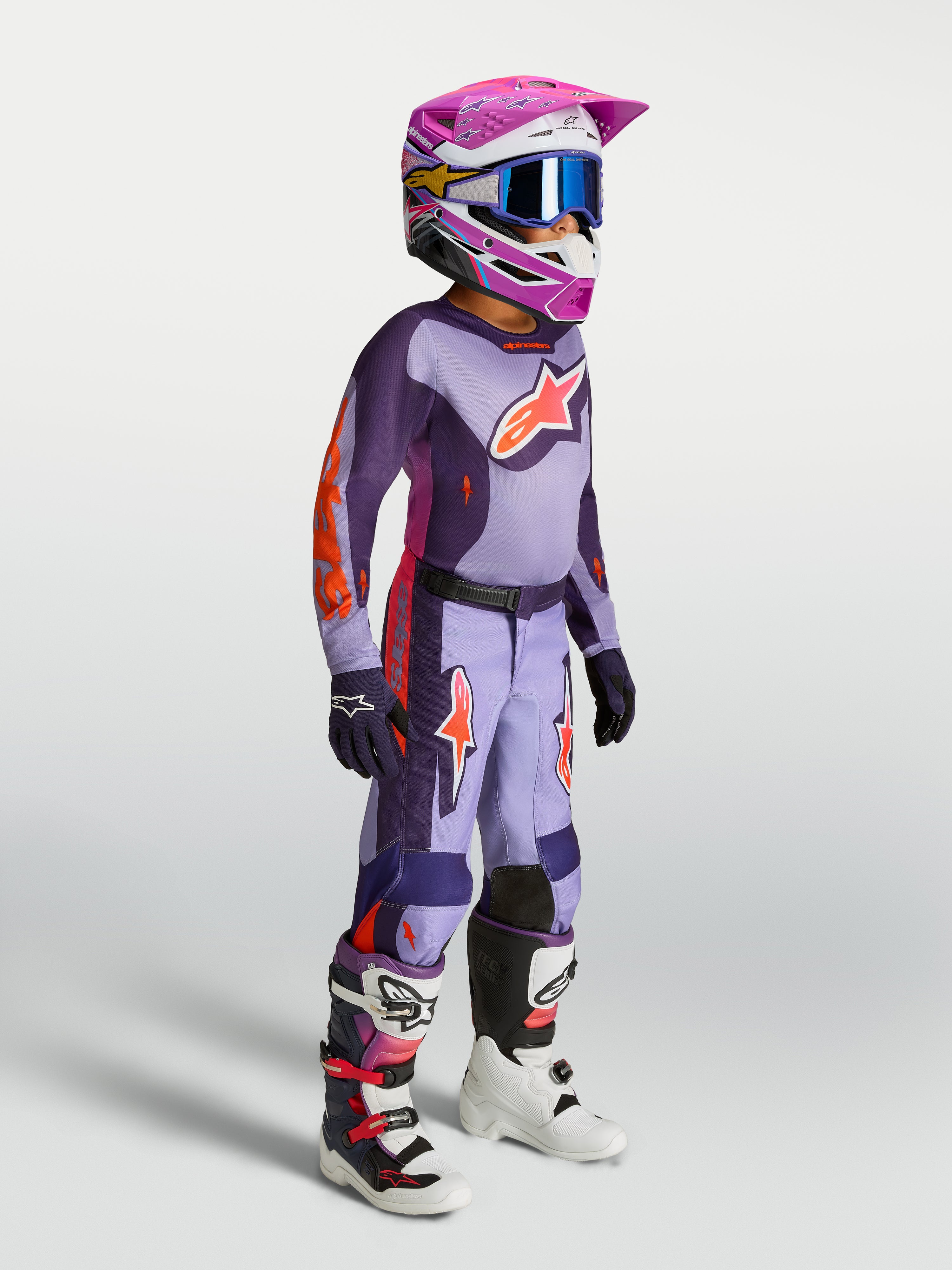 Alpinestars 2027 Youth Fluid Hunt Jersey in purple and pink fluo, youth motocross gear shown on-model with helmet and boots.