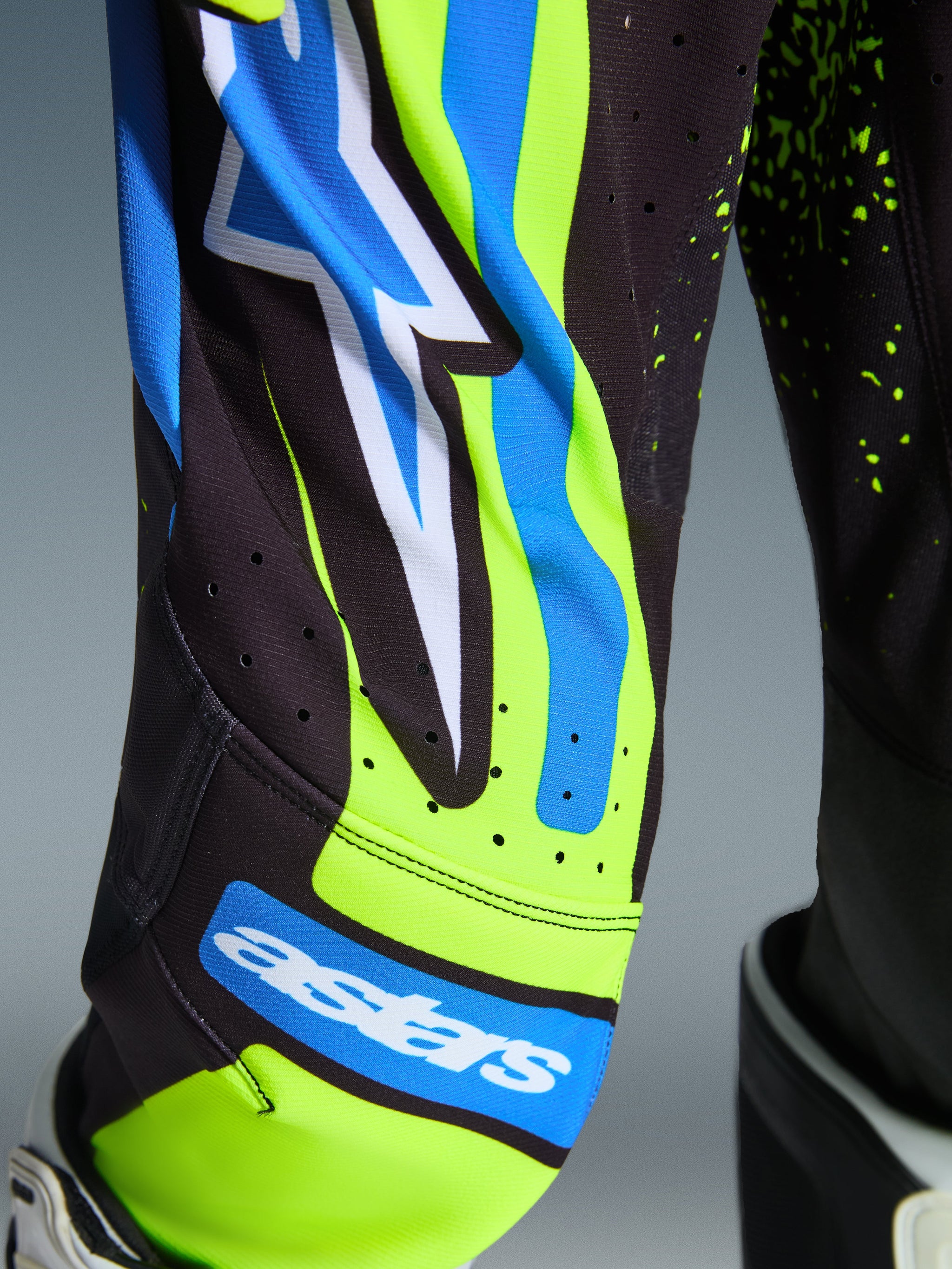 Alpinestars 2026 Youth Supertech Nomur Motocross-Ausrüstung, Nahaufnahme der Hose in Dark Navy und Yellow Fluo mit UCLA Blue Akzenten, mit Astars-Logo und lasergeschnittenen Belüftungsperforationen, technische Rennbekleidung