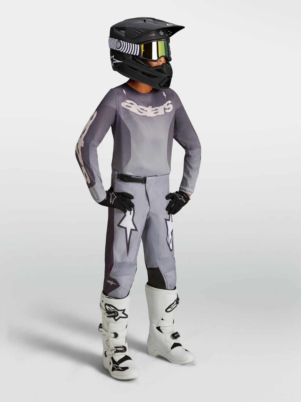 Alpinestars Youth Fluid Amber Gear Set, gray motocross jersey and pants with white racing boots and black helmet.