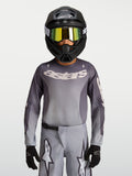 Alpinestars Fluid Jugend-Trikot Amber 2027, atmungsaktives Motocross-Trikot für Offroad, Grau und Sand, getragen mit Helm.