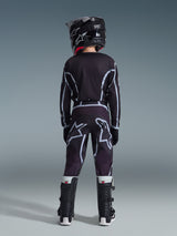 Jugendlicher Motocross-Fahrer von hinten gesehen im 2026 Youth Fluid Apex Trikot in Schwarz und Grau, passende Motocross-Hose mit großen weißen Logo-Grafiken, schwarzer Helm und schwarz-weiße Tech Series Stiefel, komplette Performance-Ausrüstung für das Offroad-Fahren.