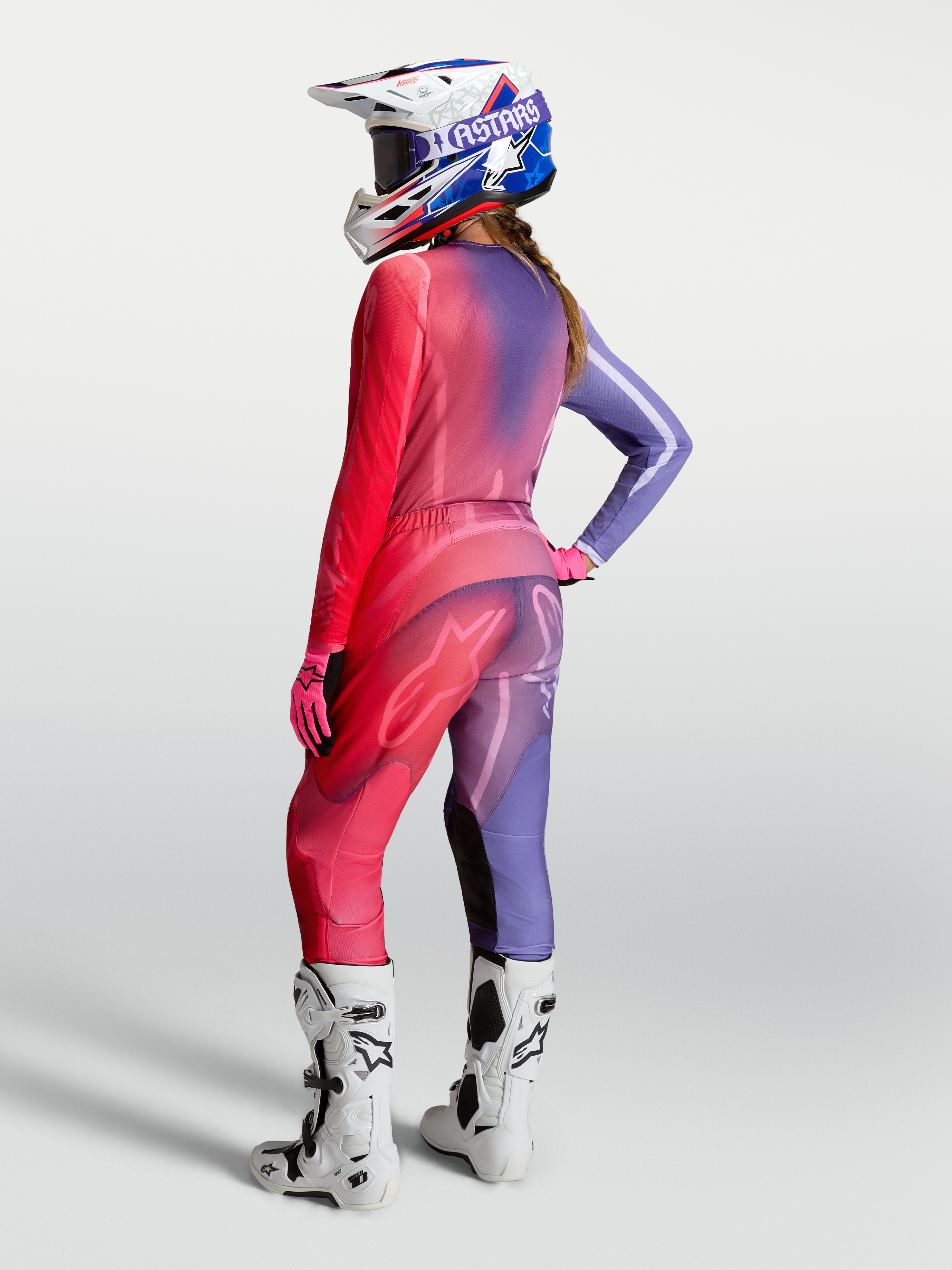 Alpinestars Stella Fluid Kepler Trikot, Damen-Motocross-Trikot in Lila und Rot, Rückansicht am Model mit passender Hose, Helm und Stiefeln.