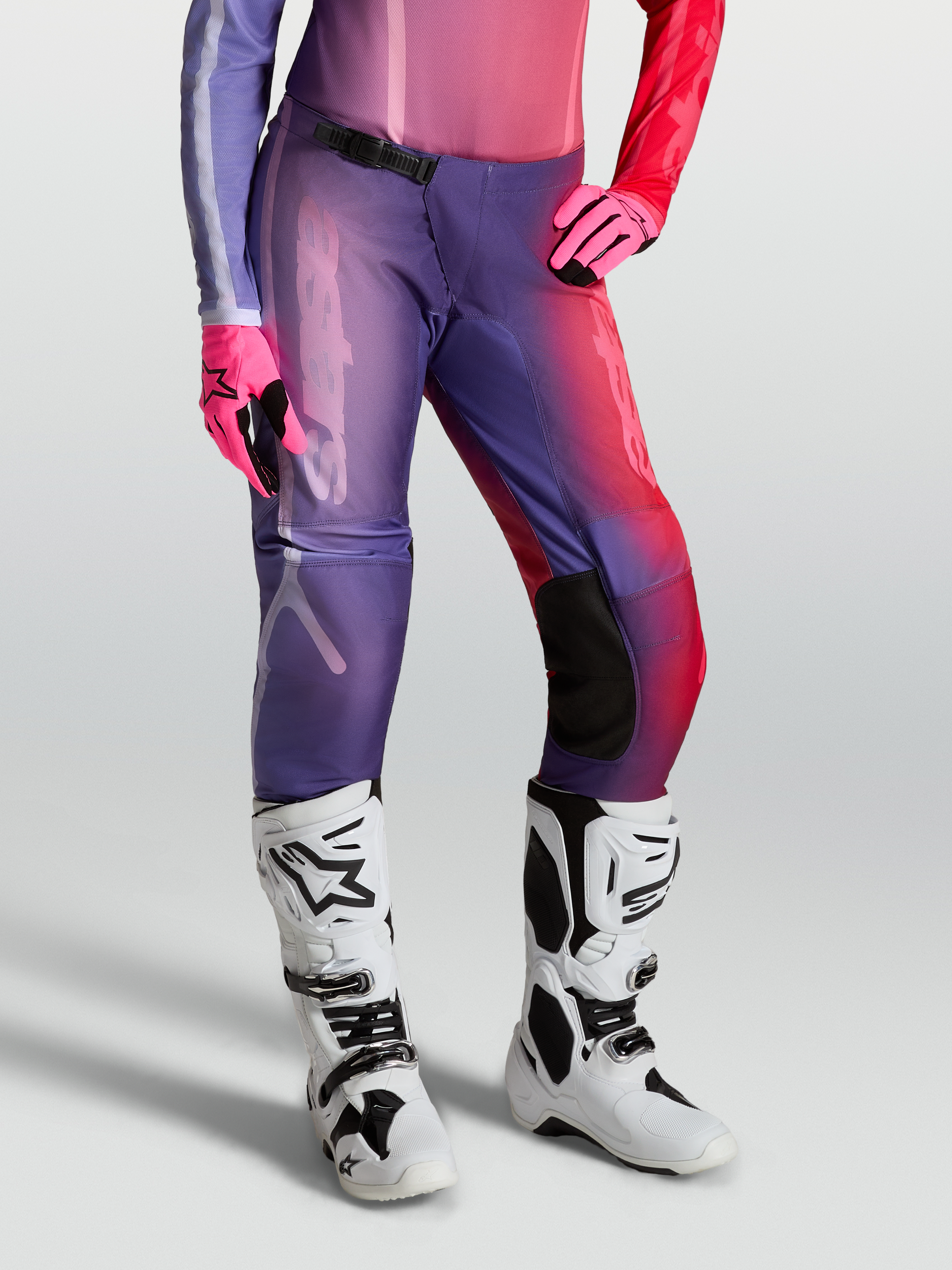 Alpinestars Stella Fluid Kepler Hose, Damen-Motocross-Ausrüstung, Lila und Rot, am Model getragen mit weißen Stiefeln und Handschuhen, strapazierfähige 600D-Polygewebe-Konstruktion.