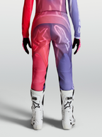 Alpinestars Stella Fluid Kepler Hose, Damen-Motocross-Hose in Lila und Rot, Rückansicht mit ergonomischem Schnitt, 600D-Polygewebe und weißen Logo-Grafiken, getragen mit weißen MX-Stiefeln.