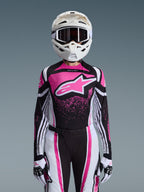 Alpinestars 2026 Stella Techstar Nomur Gear Set, Damen-Motocross-Outfit, Pink, Schwarz und Weiß mit großem Stern-Logo, passendes Jersey, Hose und Handschuhe mit einem weißen Helm, Vorderansicht auf grauem Hintergrund