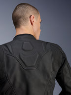 Alpinestars Dusk Leather Jacket, Black, close-up of the upper back and shoulders showing the embossed DUSK logo on a padded panel, leather accordion stretch inserts, premium bovine leather construction