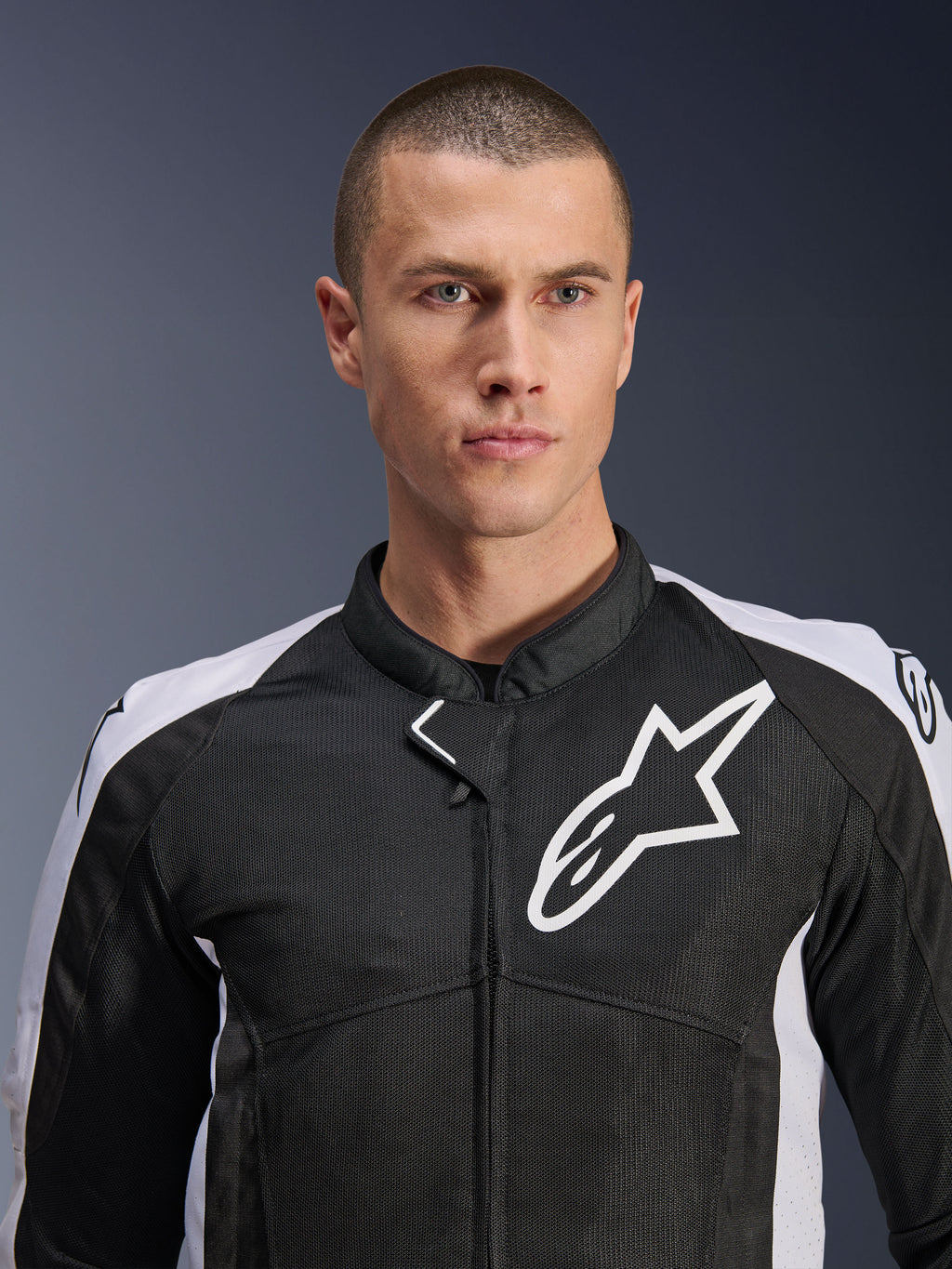 Männliches Model in der Alpinestars Viper Air V4 Jacke in Schwarz und Weiß, mit Tech-Mesh-Einsätzen für Luftzirkulation, weißem Alpinestars Stern-Logo auf der Brust, sportliche Motorrad-Straßenausrüstung
