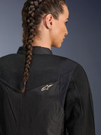 Alpinestars Stella T-Dyno Air Jacke, Damen-Motorradjacke in Schwarz, Nahaufnahme der Rückseite mit 3D-Mesh-Einsätzen an der Passe und am oberen Rücken für Luftzirkulation, kleines weißes Stern-Logo, getragen von einem Model mit geflochtenem Haar.