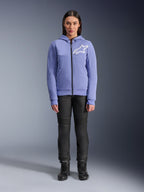 Alpinestars Stella Chrome V2 Sport Damen-Hoodie, Blau-Violett mit weißem Astars-Logo auf der Brust, technisches Fleece mit durchgehendem Reißverschluss und Kapuze, getragen mit schwarzer Motorradhose und Motorradstiefeln, lässige urbane Motorradbekleidung für Damen