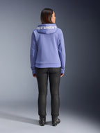 Alpinestars Stella Chrome V2 Sport Hoodie, Blau-Violett, Rückansicht einer Frau, die den Hoodie mit weißem Alpinestars-Logo auf der Kapuze trägt, kombiniert mit schwarzer Hose und Motorradstiefeln, lässige urbane Motorradbekleidung