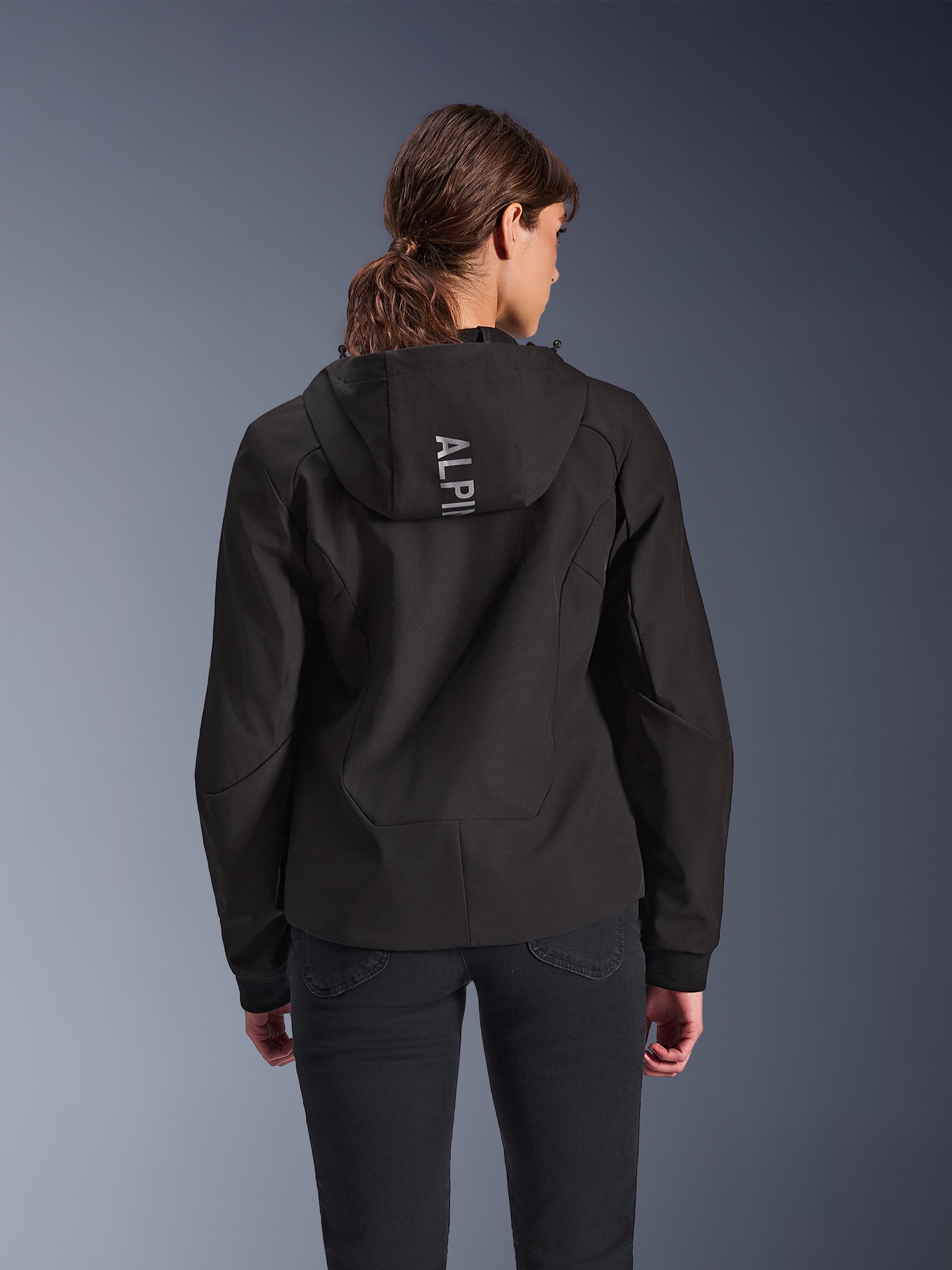 Alpinestars Stella Radium Tech Hoodie, Urbaner Motorrad-Hoodie für Damen in Schwarz, Rückansicht mit Kapuze und vertikalem silbernem Alpinestars-Branding, leichte 3-lagige winddichte Tech-Shell-Konstruktion, moderne athletische Passform