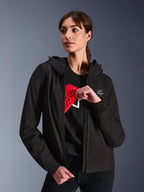 Alpinestars Stella Radium Tech Hoodie für Damen, schwarzer Urban-Riding-Hoodie, weibliches Model demonstriert rote Nucleon Flex Plus Protektoren im Inneren, leichtes 3-lagiges winddichtes Textil-Außenmaterial mit gerippten Bündchen und Logo-Patch auf der Brust, schützende Motorradbekleidung