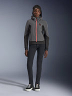 Female model wearing the Alpinestars Stella Radium Tech Hoodie, Deep Gray and Black with a bright orange zipper accent, urban motorcycle riding hoodie, paired with black slim-fit pants and sneakers, casual athletic performance gear for women.