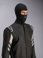 Alpinestars ZX Evo V3 Balaclava, Black, fire-resistant head sock for auto racing, worn by a model in a black racing suit with white accents, features Alpinestars logo on chin, hydration tube access port, professional motorsport protective gear