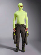 Alpinestars ZX Evo V3 Langarm-Oberteil, Yellow Fluo, getragen mit passender Sturmhaube und einem um die Taille gebundenen dunklen Rennanzug, leichte flammhemmende Basisschicht für den Autorennsport, mit Alpinestars-Logos an Kragen und Schultern
