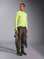 Alpinestars ZX Evo V3 Langarm-Oberteil, Yellow Fluo, getragen von einem Model mit einem um die Taille gebundenen dunkelgrauen Rennanzug und schwarzen Rennstiefeln, flammhemmende Motorsport-Funktionsunterwäsche, leichte Jacquard-Mesh-Konstruktion, professionelle Autorenn-Ausrüstung