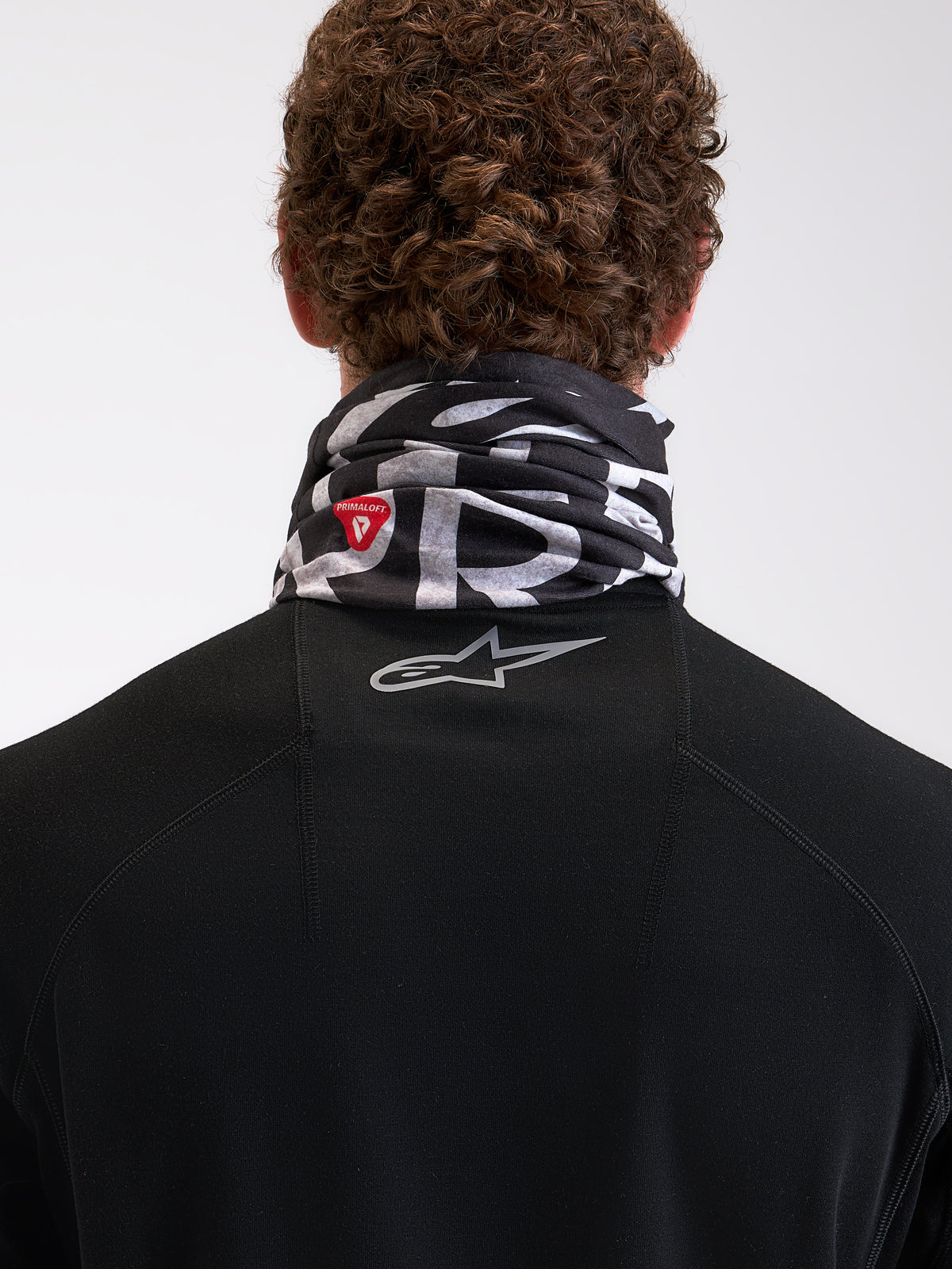 Alpinestars Buff All Terra Primaloft Halsrohr, Motorrad-Halswärmer für kaltes Wetter von hinten an einem Model getragen, Schwarz und Grau mit PrimaLoft-Isolierungslogo und reflektierendem Astar-Branding