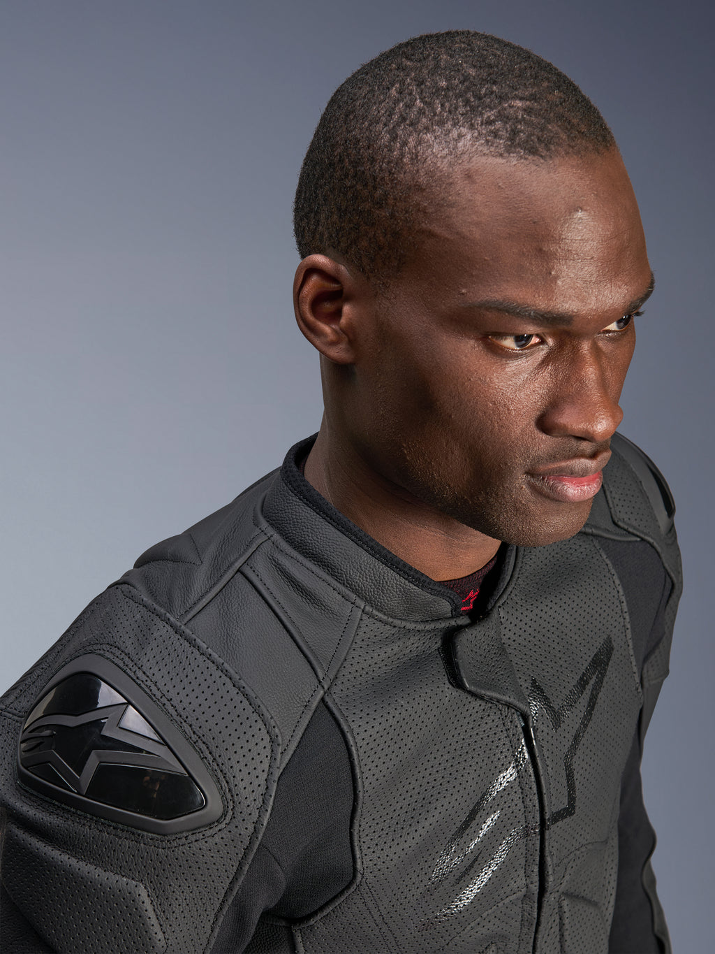 Nahaufnahme eines Models mit der Alpinestars Dusk Airflow Lederjacke, Black on Black, umfangreich perforiertes Leder für Atmungsaktivität, externe DFS-Schulterschleifer, elegantes modernes Design für sportliches Fahren