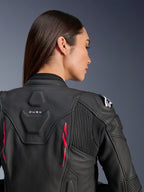 Frau trägt Alpinestars Stella Dusk Lederjacke, schwarzes Leder mit Diva Pink Akzenten und weißem Logo auf der Schulter, Rückansicht mit DUSK-Branding und Akkordeon-Stretcheinsätzen, sportliches ergonomisches Design