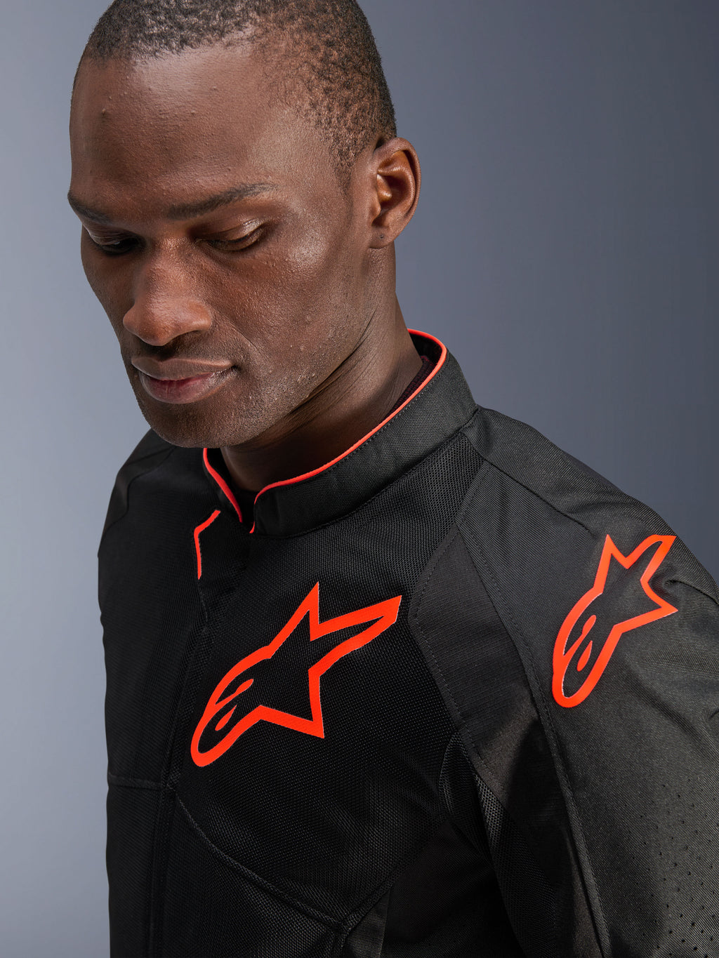 Alpinestars Viper Air V4 Jacke, Schwarz und Rot Fluo, getragen von einem männlichen Model, Nahaufnahme mit Mesh-Textileinsätzen und leuchtend neonroten Alpinestars-Logos auf Brust und Schulter, sportliche Motorrad-Straßenausrüstung