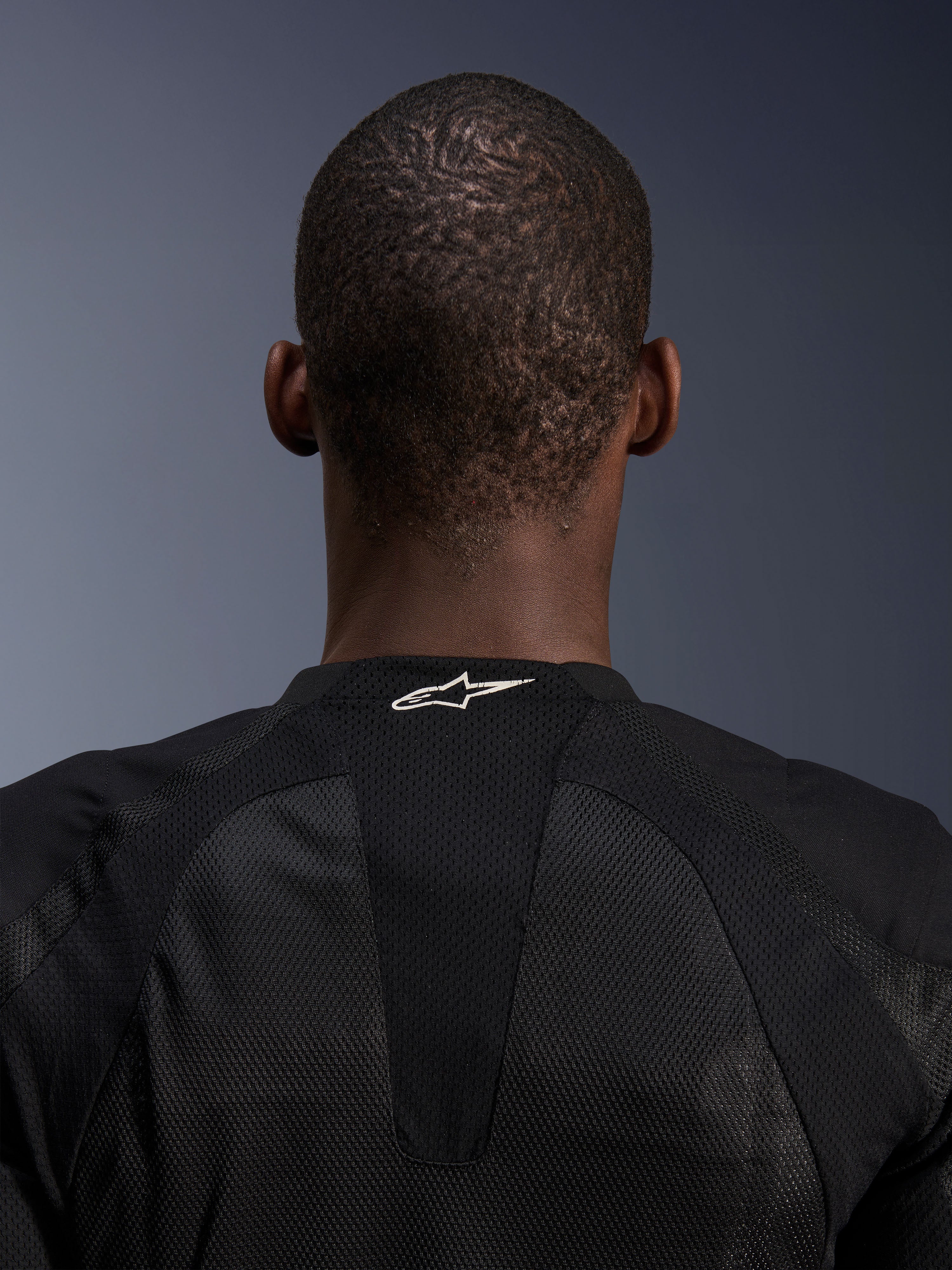 Alpinestars Troop-Air Jacke, Schwarz, Nahaufnahme des Nackenbereichs mit weißem Alpinestars-Logo auf atmungsaktivem Tech-Mesh, technische Motorradjacke für maximalen Luftstrom