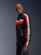 Männliches Model in der Alpinestars T-Dyno Air Jacke in Schwarz, Bright Red und Ecru, Vintage-inspirierte Textil-Motorradjacke mit 3D-Mesh-Einsätzen, markanten roten und cremeweißen Streifen sowie auffälligem Alpinestars-Branding auf dem Ärmel.
