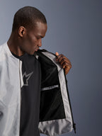 Male model wearing the Alpinestars C-1 Air Jacket in Silver, opening the front to reveal the black tech mesh interior lining and a zippered waterproof inner pocket.