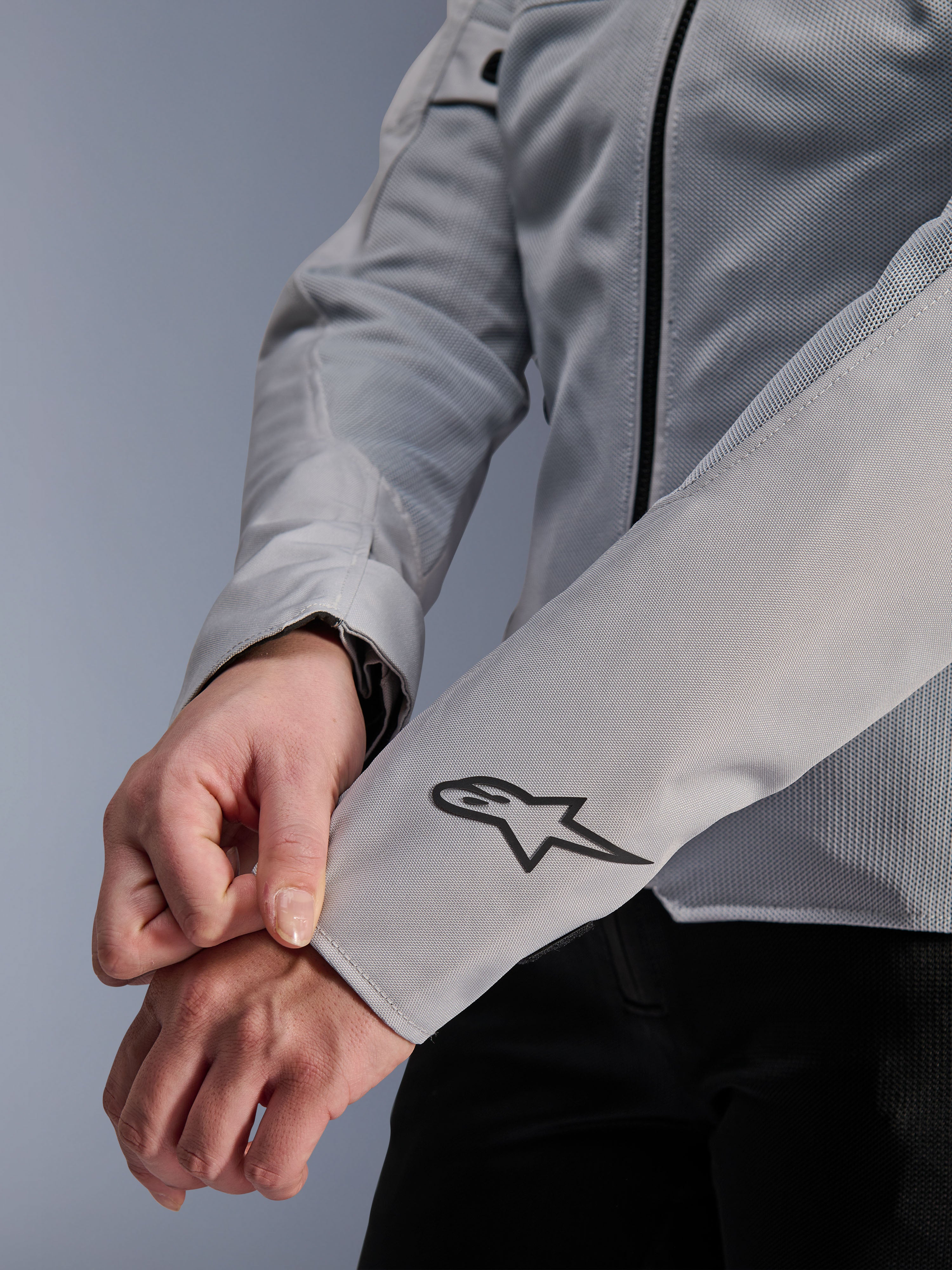 Nahaufnahme der Alpinestars Stella C-1 Air Jacke in Silber, mit technischer Mesh-Konstruktion und schwarzem Alpinestars-Logo am linken Ärmel, urbane Motorradjacke für Damen mit reflektierendem Branding.
