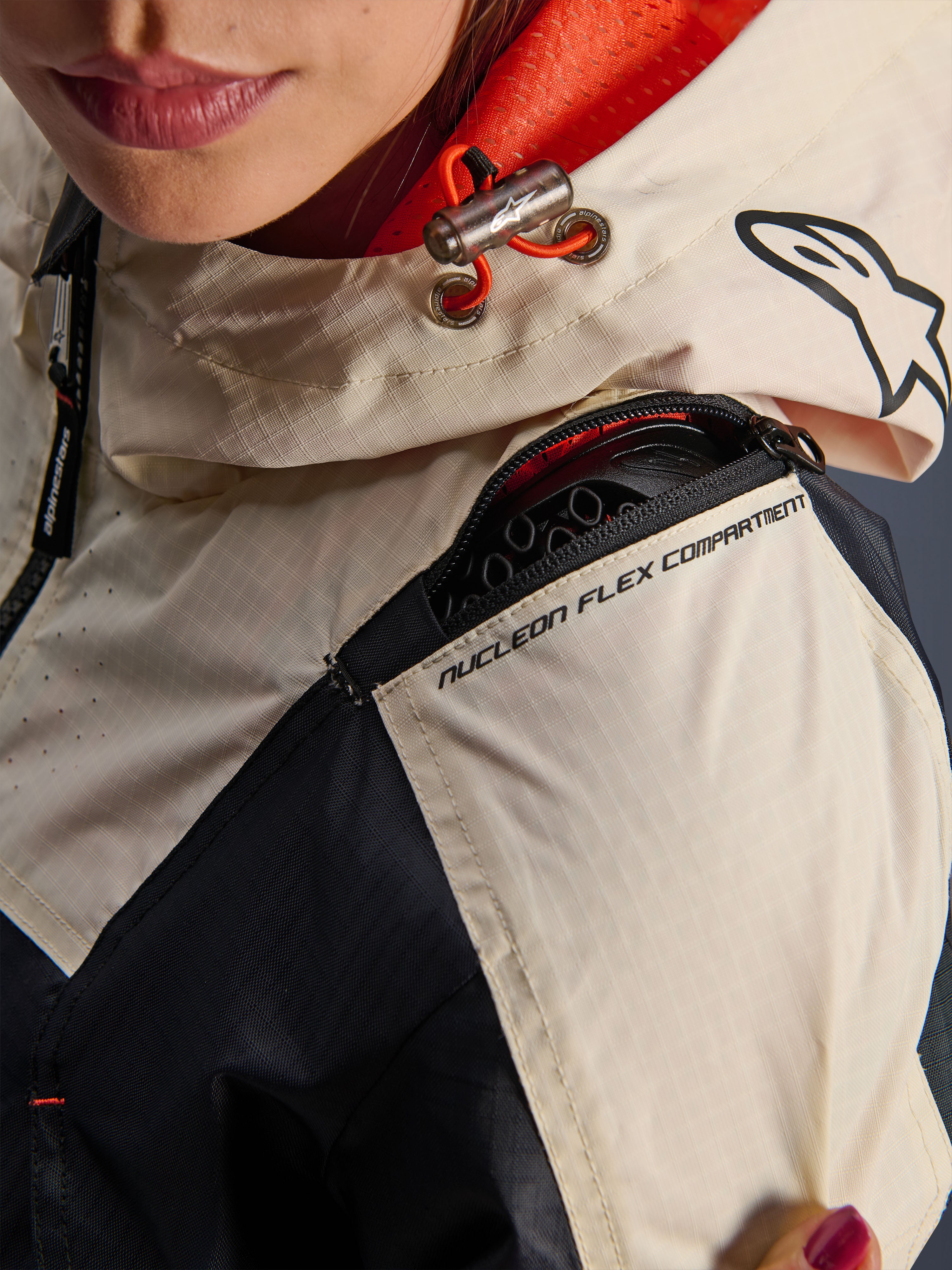 Alpinestars Molly Air Jacket, Women's Motorcycle Jacket, Black Almond, close-up view of the shoulder showing the Nucleon Flex Compartment zipper, ripstop fabric, and orange mesh lining inside the hood