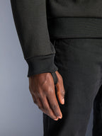 Alpinestars Chrome V2 Sport Hoodie, schwarzes Tech-Fleece, Nahaufnahme des gerippten Ärmelbündchens mit integrierter Daumenschlaufe für Stabilität beim Fahren, urbanes Motorradbekleidungs-Detail