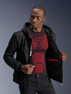 Alpinestars Chrome V2 Sport Hoodie, Schwarz, männliches Model trägt die Jacke offen, um das Innenfutter, die rote wasserdichte Tasche und das interne Branding zu zeigen, getragen über einem rot-schwarzen Baselayer, lässige urbane Motorradausrüstung