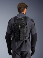 Alpinestars AT-15 Rucksack, Adventure-Motorradrucksack, Black Deep Gray, getragen über einer grauen technischen Motorradjacke, Rückansicht mit „ALL TERRA“-Branding, ergonomisches Design mit verstärkten, strukturierten Paneelen und sicheren Gurten.