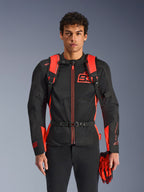 Mann mit Alpinestars MM93 AMP3 Rucksack, Leuchtrot und Schwarz, mit verstellbaren Schultergurten und Brustgurt mit Schnalle, kombiniert mit passender MM93 Motorradjacke und Handschuhen, technische Ausrüstung aus der Marc Marquez Kollektion