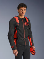 Alpinestars MM93 AMP3 Rucksack, Rot Fluo und Schwarz, getragen von einem Model mit passender schwarz-roter MM93 Motorradjacke und Handschuhen, Vorderansicht mit Fokus auf die verstellbaren Schultergurte und die Brustschnalle, technische vom Rennsport inspirierte Ausrüstung.