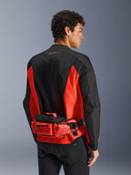 Alpinestars MM93 Hüfttasche, Motorrad-Gürteltasche, Hellrot und Schwarz, getragen über einer passenden schwarz-roten Motorradjacke, mit Reißverschlussfächern und Marc Marquez MM93-Branding, strapazierfähige Textilkonstruktion für den Motorradsport
