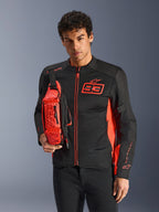 Mann mit Alpinestars MM93 Waist Bag, Rot Fluo und Schwarz, als Crossbody-Tasche über einer passenden schwarz-roten Motorradjacke getragen, mit Marc Marquez 93-Logo, sportliches Racing-Design