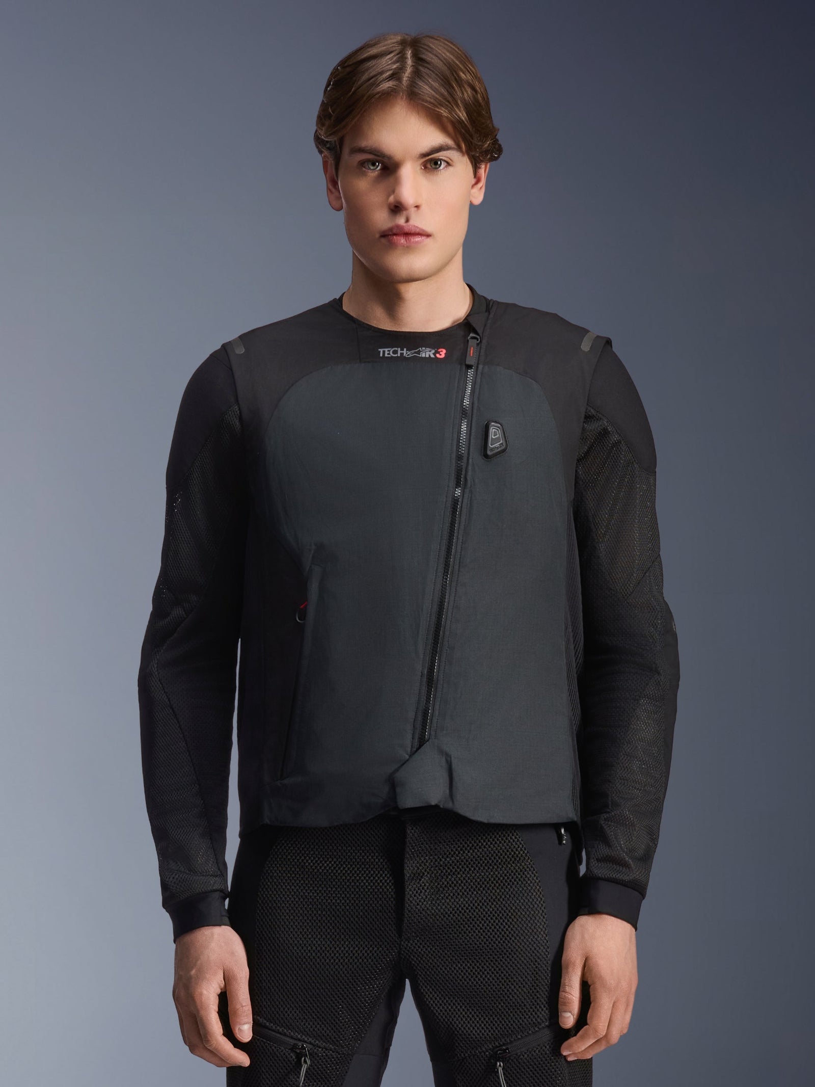Alpinestars Tech-Air 3 V2 System, Motorcycle Airbag Vest, Black, worn by a male model over a black mesh riding layer, featuring a diagonal front zipper and integrated electronic display, lightweight and streamlined design for road safety