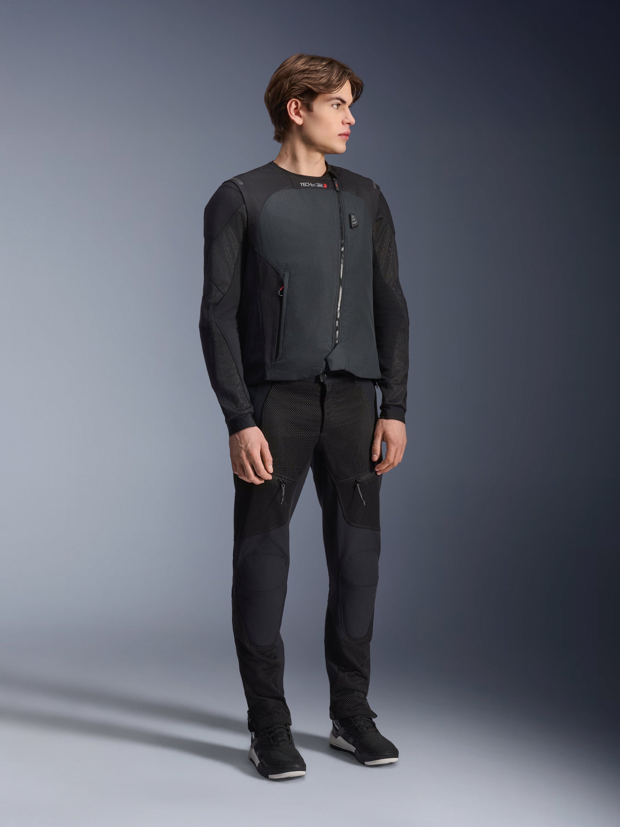 Alpinestars Tech-Air® 3 V2 System, autonomous motorcycle airbag vest in Black, worn by a male model with black mesh riding gear and pants, sleek and lightweight technical safety gear for road riders